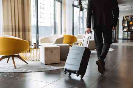 © Drobot Dean - stock.adobe.com Mann zieht Koffer in Hotellobby